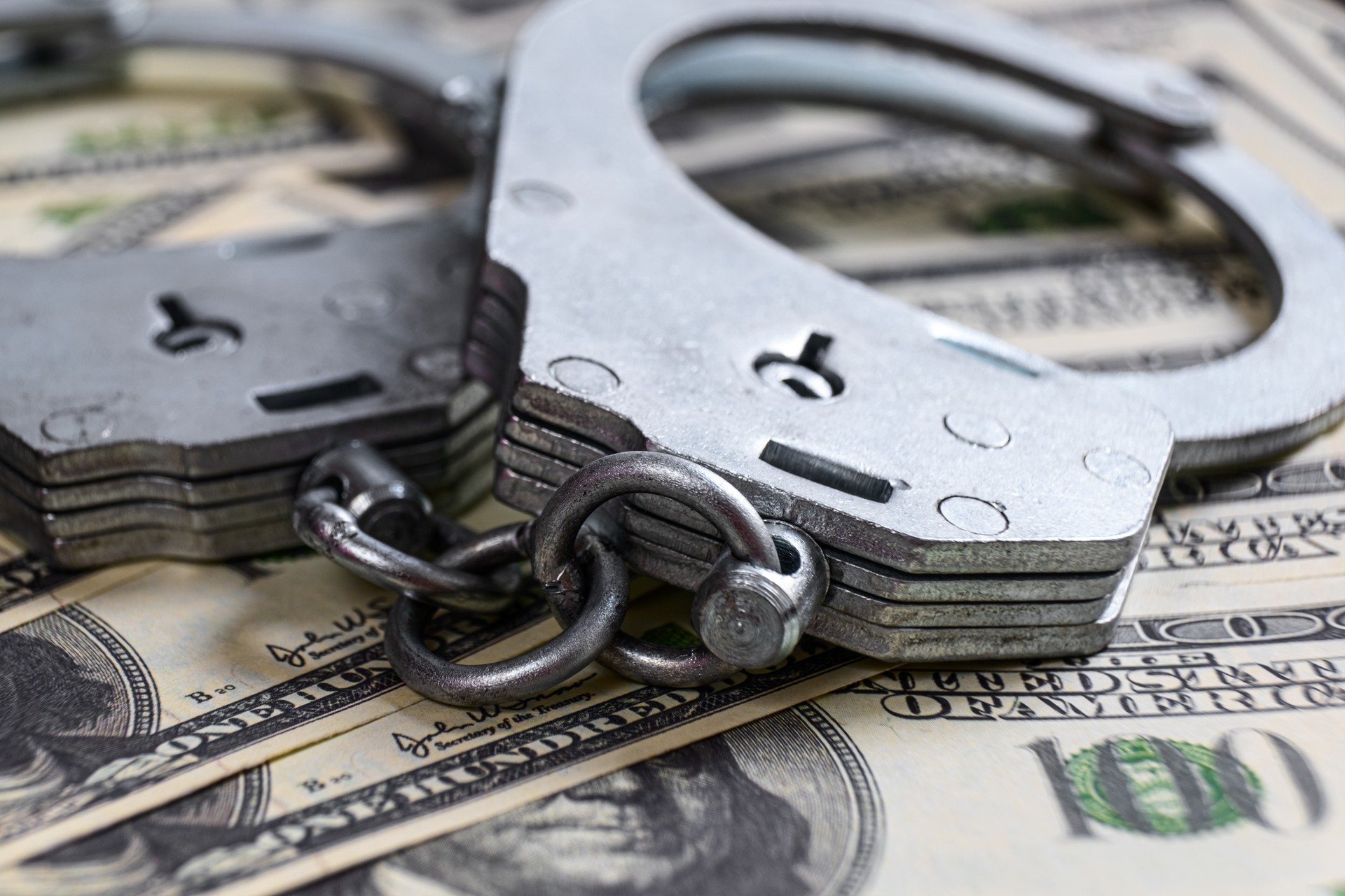 Cash in US Dollars, Real Handcuffs. The Concept of Arrest, Corruption, Bail, Crime, Bribery or Fraud.